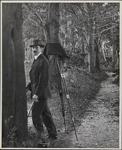 [Photographer with tripod set up in wooded area]