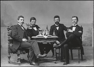 [Portrait of four men seated at a table.]