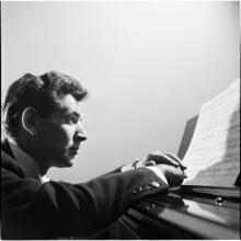 Leonard Bernstein [Leonard Bernstein at a piano looking at sheet music.]