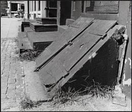 [Cellar door, metal covered steps, and cobblestone paving at 165 John Street.]