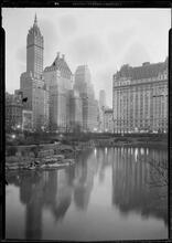New York City views. Dusk view of Plaza buildings over park lake.