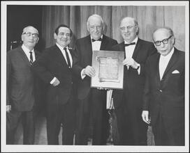 [Charles H. Silver holding an award, surrounded by Charlie Cohn, Irving Jacobson, Menasha Skulnik and an unidentified man.]