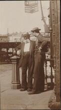 [Men talking in front of a gun store.]