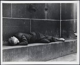 [Man sleeping in a public place.]