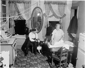 Kitchen Interior: Father and Baby with Mother Ironing