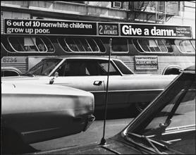 View of bus on Madison Avenue between 96th and 97th Streets, advertisement on bus reads "6 out of 10 non-white children grow up poor - give a damn"