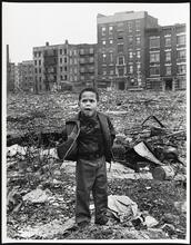 Among the last residents, [an] African-American boy standing in rubble, his "neighborhood," with abandoned buildings in the background.
