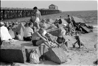 [People sunbathing on rocks at Coney Island beach.]