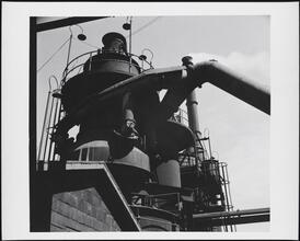 [Factory building, machinery on roof.]