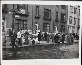[Spectators at sidewalk art show.]