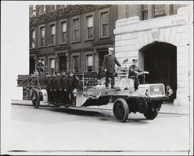 [Firemen riding on fire engine.]