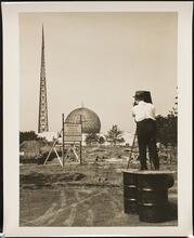 [New York Worlds' Fair. Norman Wurts photographing site of Beech-Nut Building. Construction view (With the Trylon and Perisphere in the background.).]