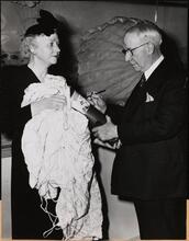 [Al Smith signing a bomb being held by Mrs. Eddie Rickenbacker.]