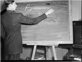 [Boy writing on a blackboard.]
