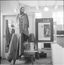 Bloomingdale's [Display in Bloomingdale's featuring a mannequin with a coat and "As Seen in LOOK Magazine" posters surrounding the display.]