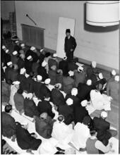 [Man speaking to an audience.]