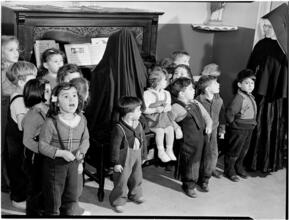 [Children singing as a nun plays the piano.]