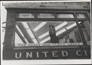 [Fur coat display in store window.]