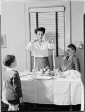 [Woman praying as her children watch.]