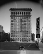 [Looking west across a parking lot to the Flatiron Building, 949 Broadway.]
