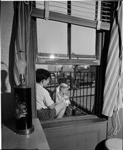 [Children watering a plant on a fire escape.]