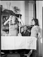 [Woman praying as her children watch.]