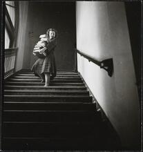 Columbia University [Woman carrying large stack of books downstairs.]