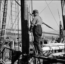 Waterfront. [Man walking near the mast of a boat.]