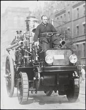 [Fireman driving early fire engine.]