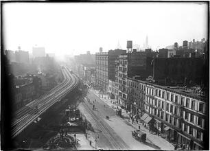 [Street scene with elevated railroad curve and bridge in distance]