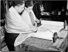 [Man and boy reading a torah scroll.]