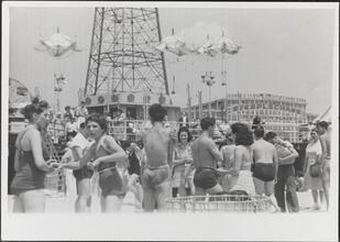 [Crowd on Coney Island beach, boardwalk and parachute ride in background.]