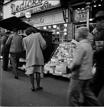 Newsstand [People browsing through magazine racks at a busy sidewalk newsstand.]