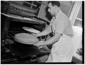 [Man taking bread out of an oven.]
