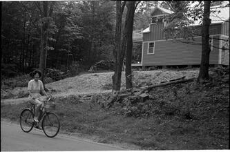 [Unidentified woman riding bicycle.]