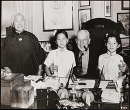 [Al Smith hugging two girls at his desk.]