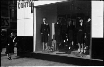 [Woman walking past window display.]