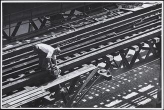 [Sawing through supports of catwalk, after railing has been removed.]