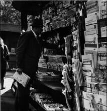 Newsstand [People browsing through magazine racks at a busy sidewalk newsstand.]