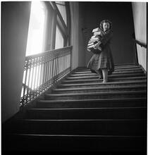 Columbia University [Women carrying a stack of books down a flight of stairs.]