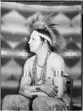 [Man in tradional Native American clothing.]