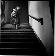 Columbia University [Woman with a large stack of books walking down a flight of stairs.]