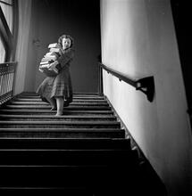 Columbia University [Woman with a large stack of books walking down a flight of stairs.]
