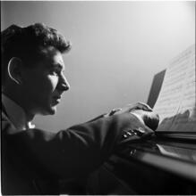 Leonard Bernstein [Leonard Bernstein at a piano looking at sheet music.]