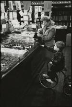 The 5 and 10 [Woman shopping with a boy riding a tricycle in Woolworth's.]
