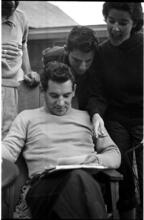 Leonard Bernstein [Leonard Bernstein looking at photographs as people look over his shoulder.]