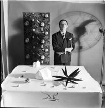 Salvador Dali: Rugs [Salvador Dali standing in front of a rug he designed near a table with objects.]