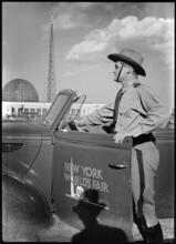 [New York World's Fair police officer and patrol car with frames of the Trylon and Perisphere in the background.]