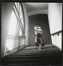 Columbia University [Woman carrying a large stack of books downstairs.]