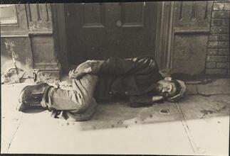 [Homeless man sleeping on sidewalk.]
